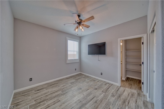 unfurnished bedroom featuring a spacious closet, ceiling fan, a closet, and light hardwood / wood-style floors