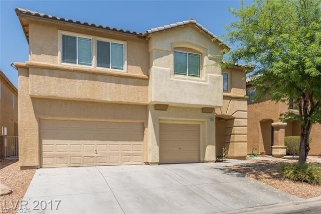 view of front of home featuring stucco siding, an attached garage, a tiled roof, and driveway