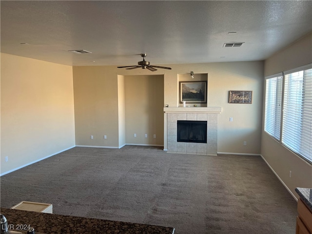 unfurnished living room featuring a tile fireplace, ceiling fan, and carpet flooring