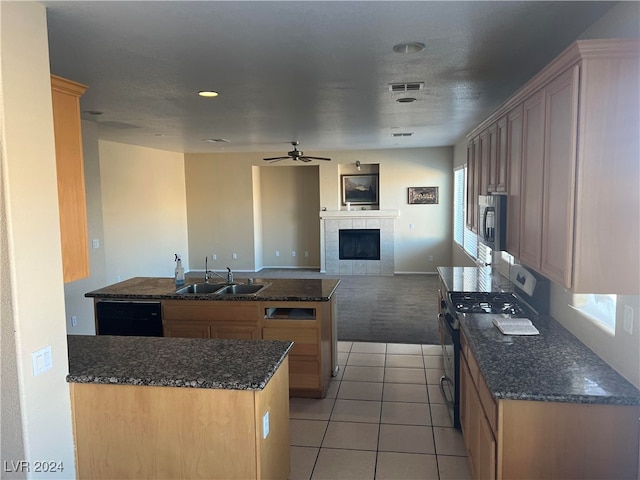 kitchen with light tile patterned floors, ceiling fan, a kitchen island, sink, and gas range