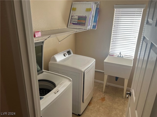 washroom featuring light tile patterned flooring, washing machine and clothes dryer, and sink