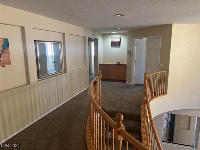 corridor featuring a textured ceiling and carpet