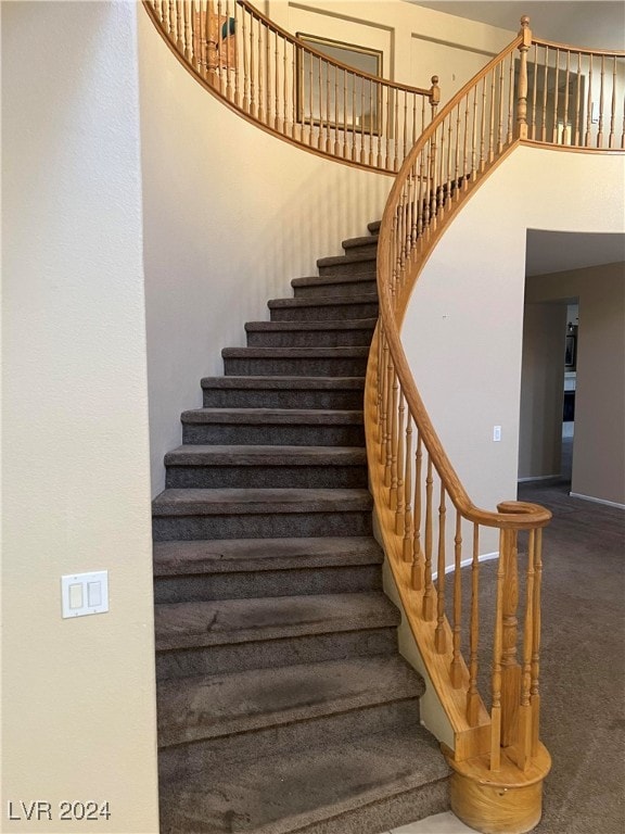 stairway featuring a towering ceiling