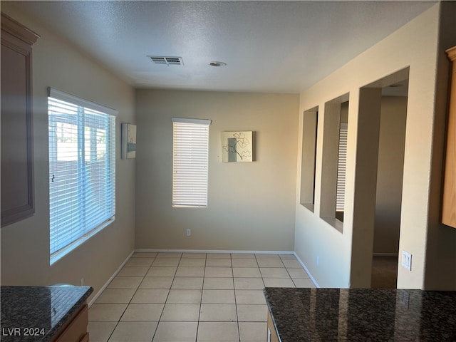 unfurnished dining area featuring a textured ceiling and light tile patterned flooring