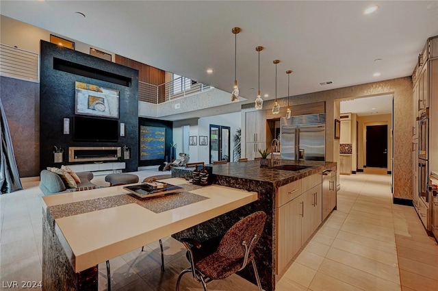 kitchen featuring appliances with stainless steel finishes, a large island, hanging light fixtures, light tile patterned floors, and sink