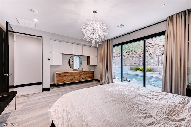 bedroom with light hardwood / wood-style flooring, a chandelier, and access to exterior