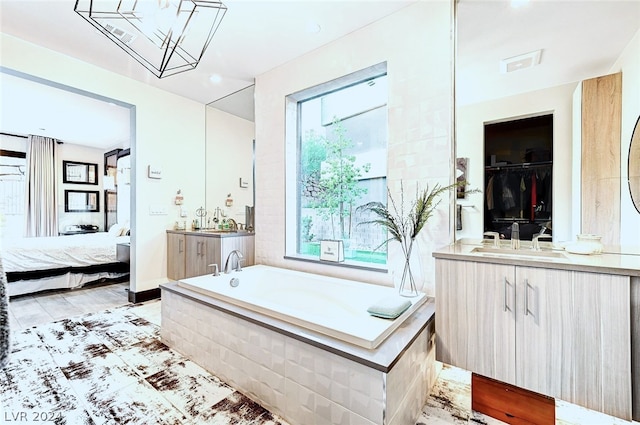 bathroom featuring tile patterned floors, vanity, and tiled bath