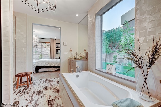 bathroom with vanity, a wealth of natural light, a relaxing tiled tub, and hardwood / wood-style floors