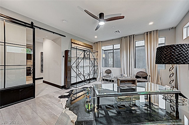 interior space with ceiling fan, a barn door, and light hardwood / wood-style flooring