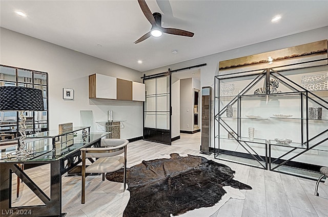 office area featuring a barn door, ceiling fan, and light hardwood / wood-style floors