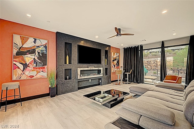 living room with light hardwood / wood-style flooring, a fireplace, expansive windows, and ceiling fan