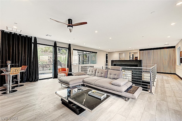 living room featuring ceiling fan, light hardwood / wood-style flooring, and a fireplace