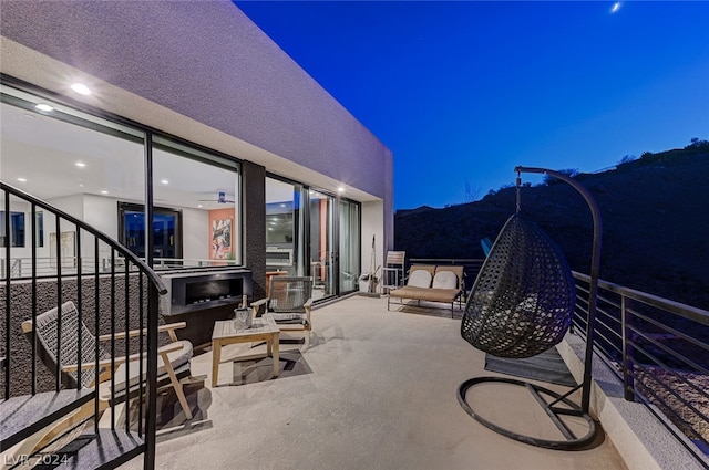 patio at twilight featuring a mountain view and a balcony