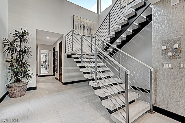 stairs featuring a high ceiling, tile patterned floors, and a healthy amount of sunlight