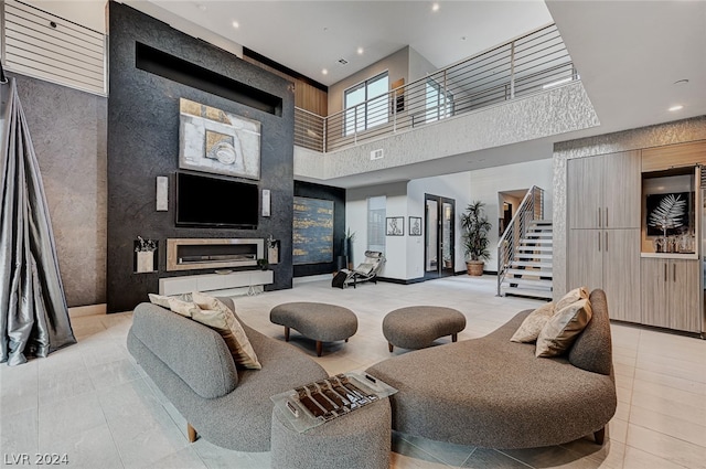 living room with light tile patterned flooring, a large fireplace, and a high ceiling