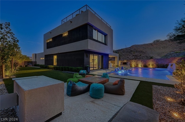 rear view of property featuring a yard, pool water feature, a patio, and a balcony