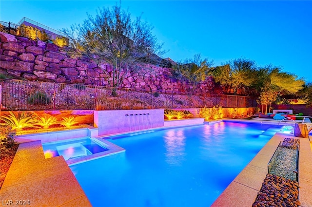 pool at dusk featuring an in ground hot tub