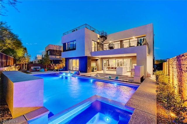 rear view of property with a balcony, a patio, pool water feature, and a swimming pool with hot tub