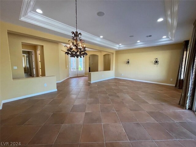 unfurnished living room with a tray ceiling, dark tile patterned flooring, and a notable chandelier