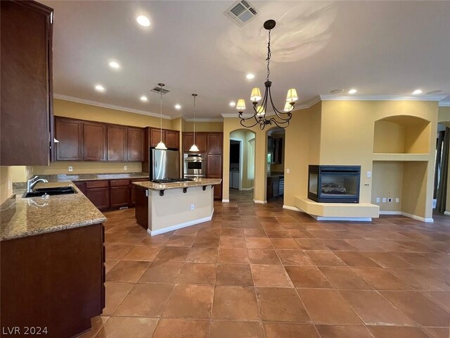 kitchen with a center island, decorative light fixtures, stainless steel appliances, and a multi sided fireplace