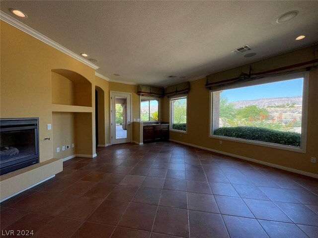 unfurnished living room featuring built in shelves, ornamental molding, and dark tile patterned floors