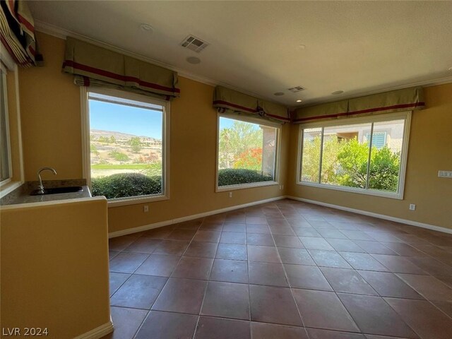 tiled empty room featuring crown molding and sink