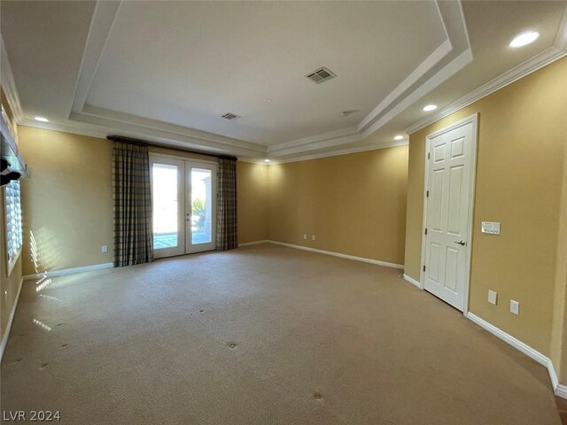 carpeted spare room with french doors, a tray ceiling, and ornamental molding