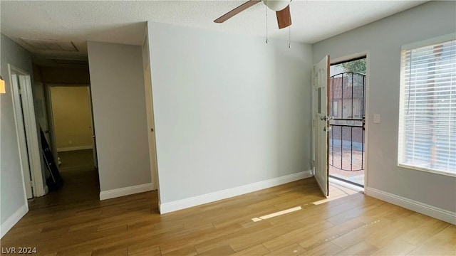 spare room featuring light wood-type flooring, a textured ceiling, and ceiling fan