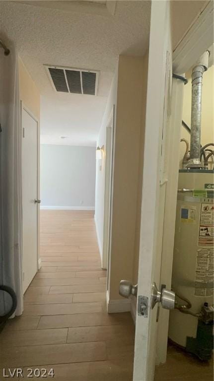 corridor with gas water heater and light hardwood / wood-style flooring