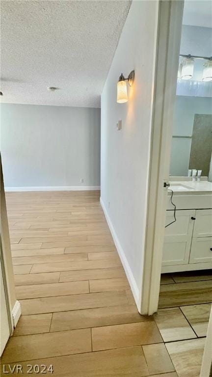 hall with light hardwood / wood-style floors and a textured ceiling