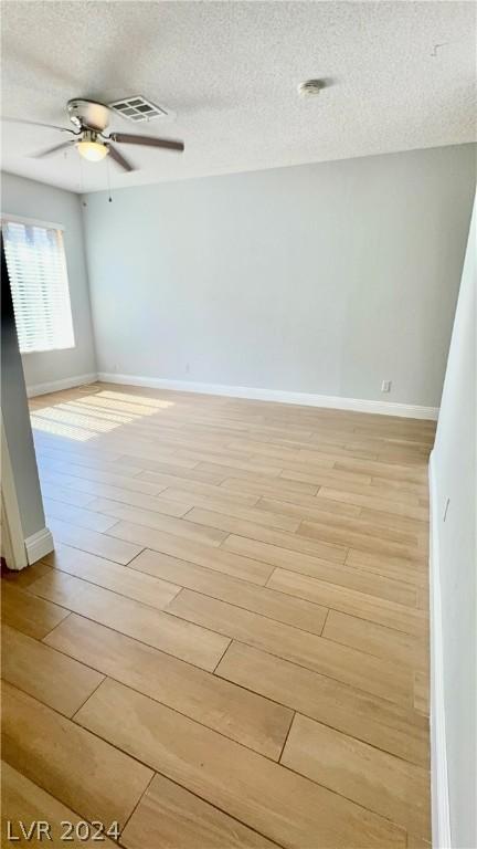 spare room with ceiling fan, light wood-type flooring, and a textured ceiling