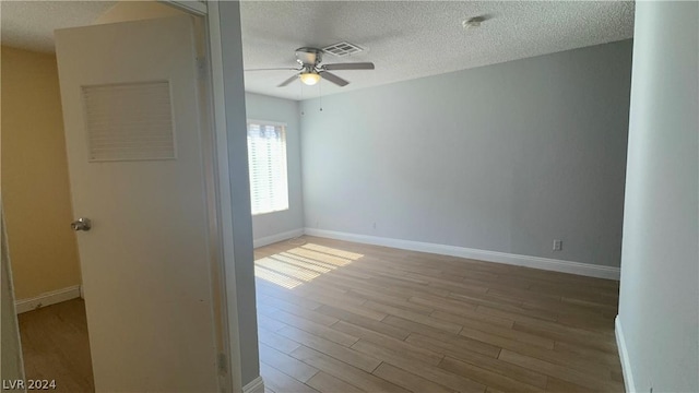 unfurnished room with a textured ceiling, ceiling fan, and light hardwood / wood-style flooring