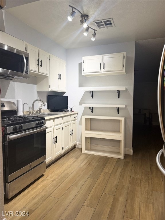 kitchen with sink, light hardwood / wood-style floors, stainless steel appliances, and white cabinetry