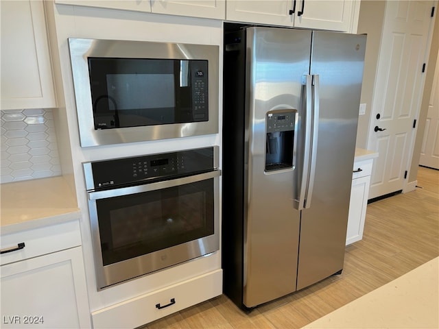 kitchen featuring backsplash, white cabinetry, light hardwood / wood-style flooring, and appliances with stainless steel finishes