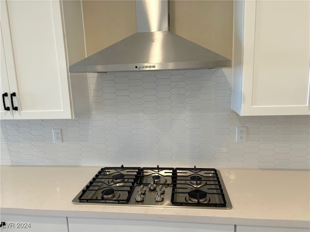 kitchen with decorative backsplash, white cabinetry, wall chimney exhaust hood, and gas cooktop