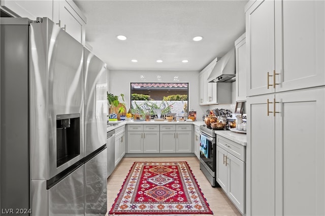 kitchen featuring stainless steel appliances, light hardwood / wood-style floors, white cabinetry, and premium range hood