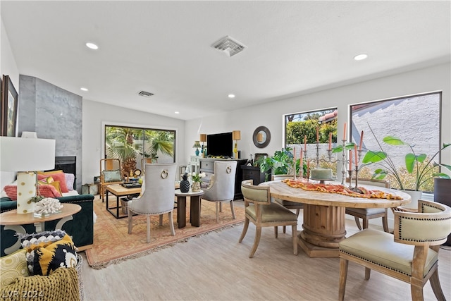 dining space featuring a wealth of natural light, a high end fireplace, light hardwood / wood-style floors, and lofted ceiling