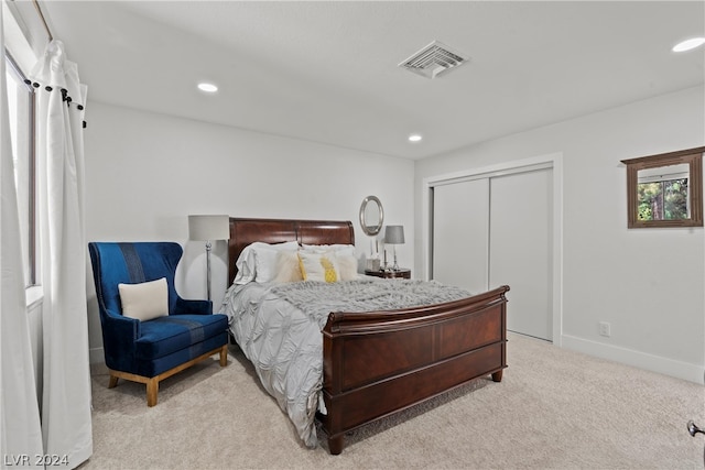 bedroom featuring a barn door, light carpet, and a closet