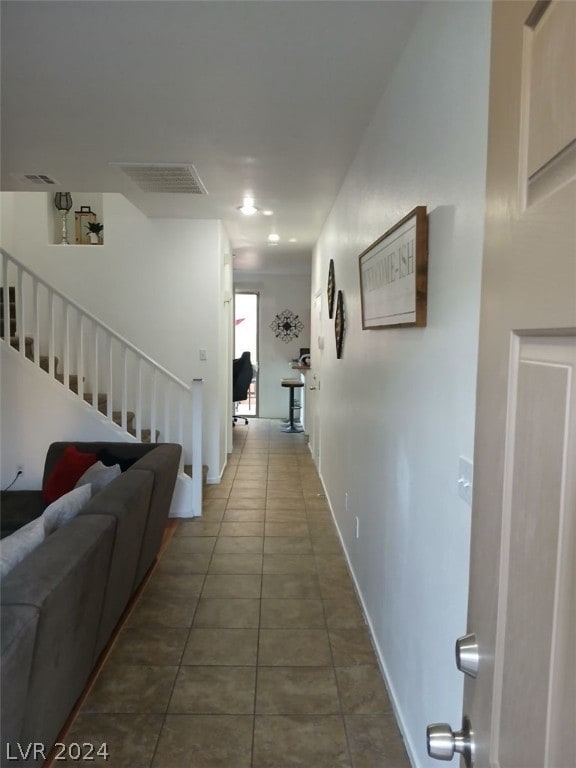 corridor with baseboards, stairs, visible vents, and tile patterned floors