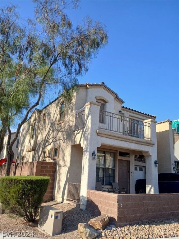 mediterranean / spanish-style home with fence, a balcony, and stucco siding