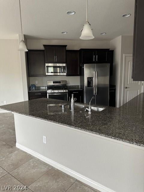 kitchen featuring stainless steel appliances, a textured ceiling, dark stone counters, and decorative light fixtures