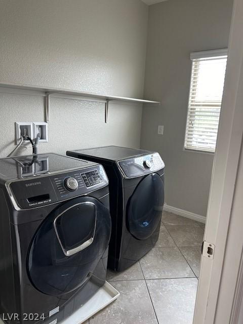 clothes washing area featuring light tile patterned floors and washing machine and clothes dryer