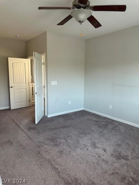 empty room featuring dark colored carpet and ceiling fan