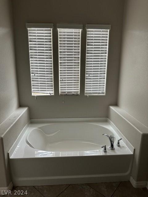 bathroom with tile patterned flooring, a healthy amount of sunlight, and a bathtub