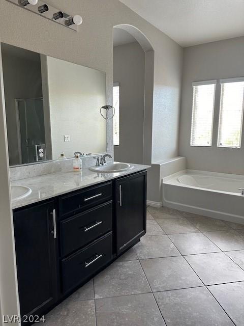 bathroom with tile patterned flooring, vanity, a tub, and a textured ceiling