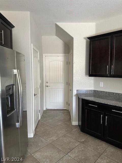 kitchen with stainless steel refrigerator with ice dispenser, a textured ceiling, and light tile patterned floors