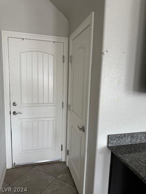 doorway with lofted ceiling and dark tile patterned flooring