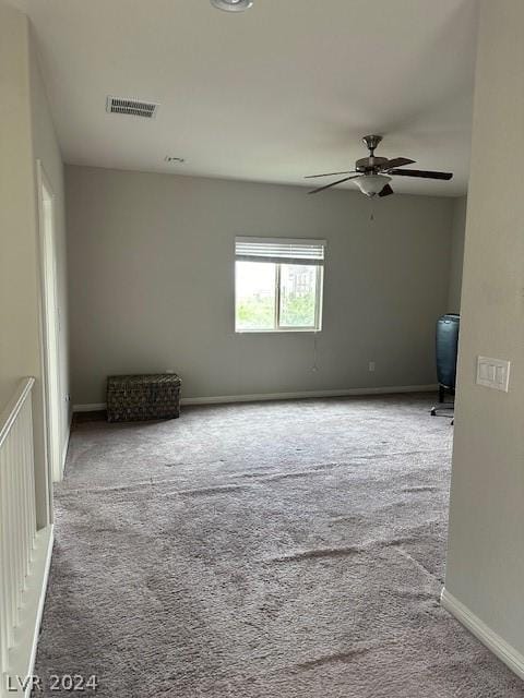 empty room featuring ceiling fan and light carpet