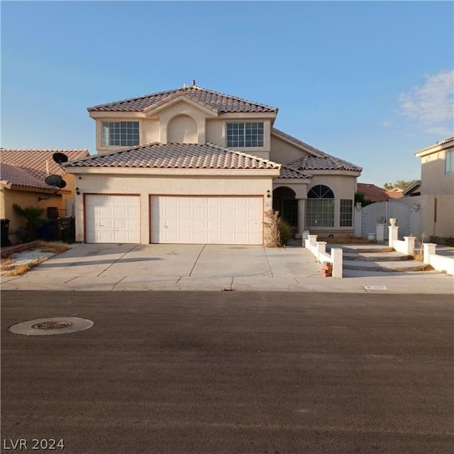 mediterranean / spanish home featuring concrete driveway, a tiled roof, an attached garage, fence, and stucco siding