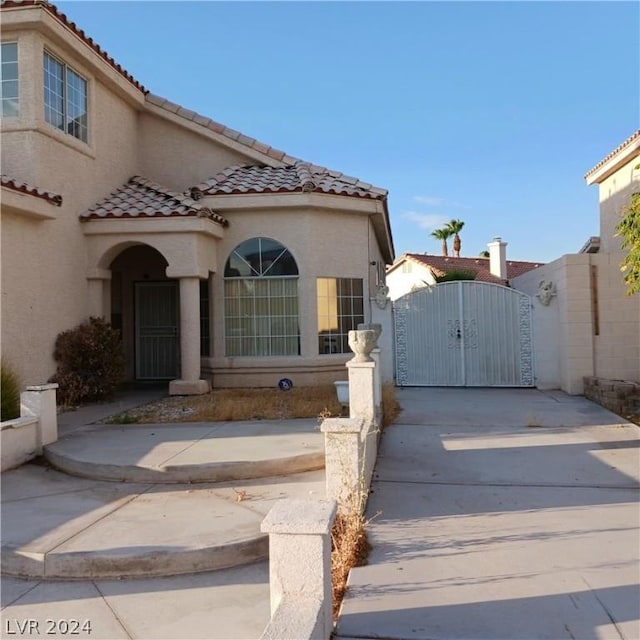 view of front of property with a tiled roof, a gate, and stucco siding